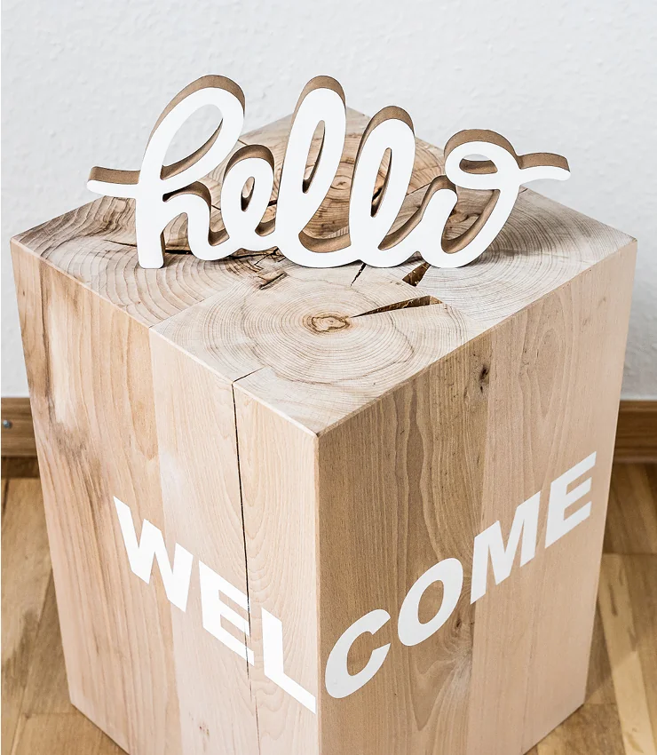 Hölzerner Schriftzug Hello auf einem Holzblock als Willkommensgruß